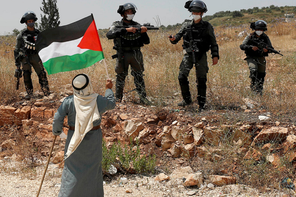 Israeli regime forces confront a Palestinian man waving Palestinian flag