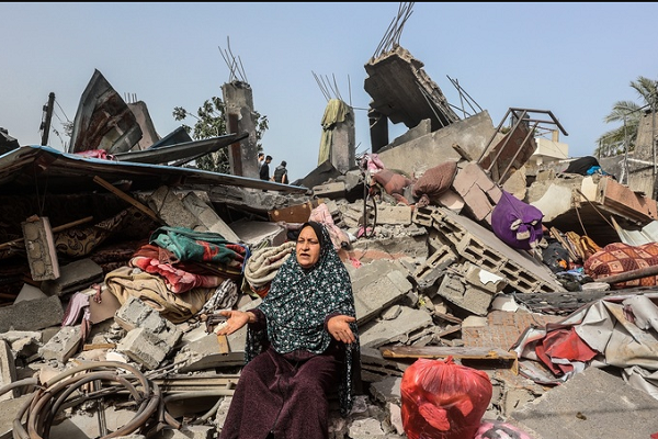 A Palestinian woman is sitting on the rubble of her house destroyed in an Israeli attack.
