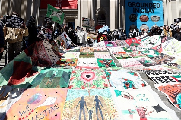 Demonstrators cover steps of The Met with large patchwork blanket displaying messages of solidarity with Palestine