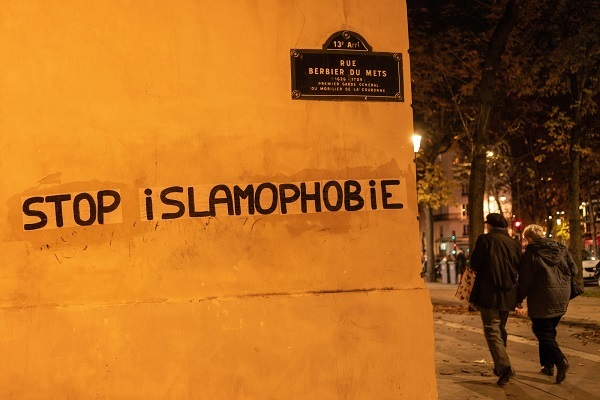 People walk past graffiti reading ‘Stop Islamophobia’ in Paris, France