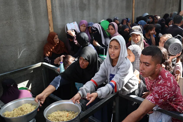 Palestinians gather to receive food portions from a charity kitchen in the Nuseirat refugee camp, located in the central Gaza Strip a week after a ceasefire came into effect.