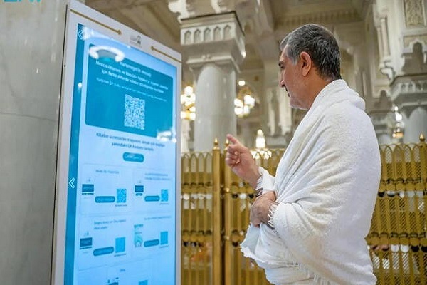 Pilgrim at the Grand Mosque in Mecca interacts with the AI-powered Manarat Al-Haramain Robot, which leverages advanced technologies to enhance the spiritual experiences of pilgrims.