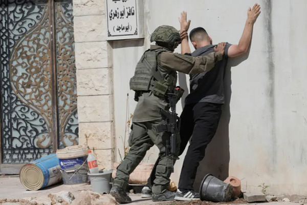 An Israeli soldier pats down a Palestinian man in the occupied West Bank refugee camp of Tulkarem on July 6