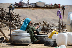 زن عشایر ایل خمسه در حال پر کردن مشک است.